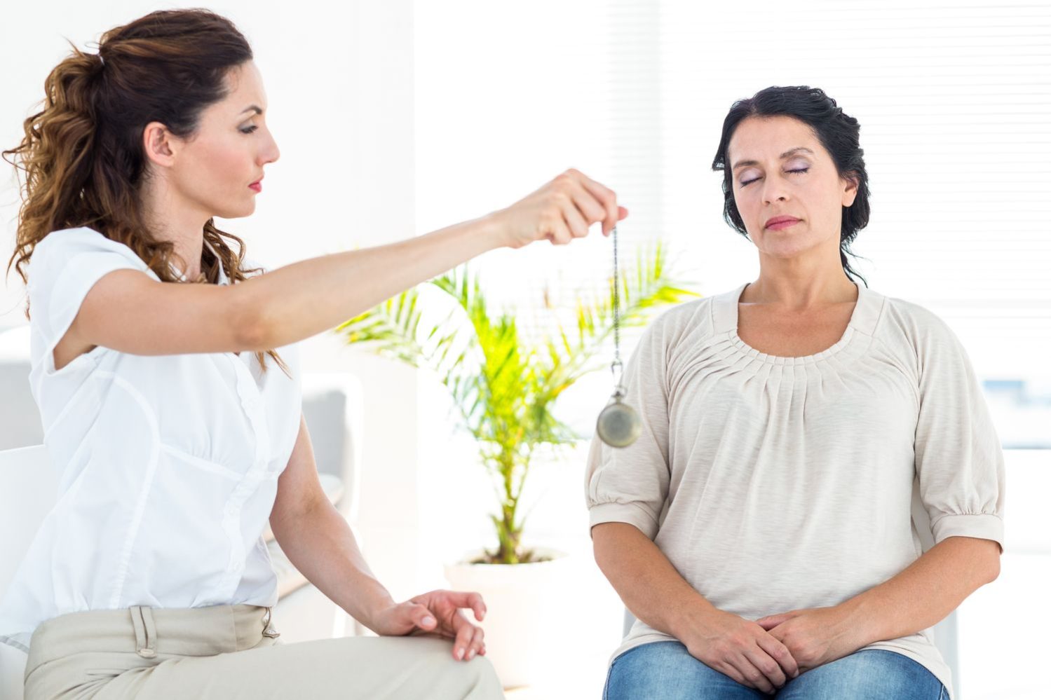 Therapist hypnotizing her patient on white background